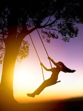 Девочка на качелях на фоне заката